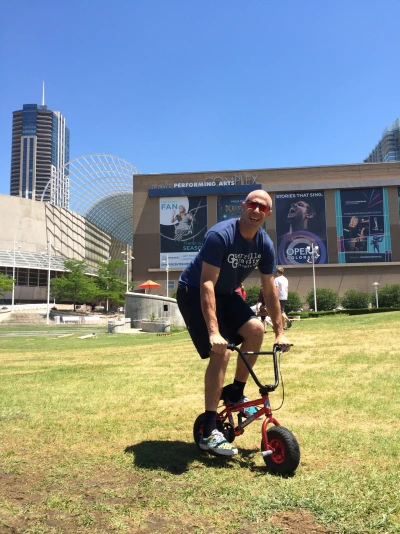 Man riding children's bicycle in Denver, CO IV therapy Denver